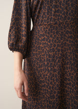 Woman wearing a brown leopard print satin dress against a plain background