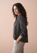 Woman wearing a black and white check shirt against a beige background