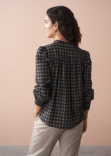Woman wearing a black and white checkered shirt against a beige background