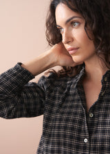 Woman wearing a plaid shirt against a beige background