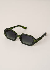 Green tortoiseshell sunglasses on a light beige background