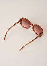 Brown sunglasses with tortoiseshell frame on a light beige background