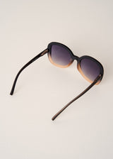 Sunglasses with black frame and gradient lenses on a light beige background