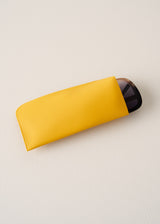 Yellow case with a black sunglasses on a light beige background