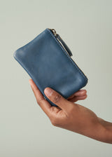 Hand holding a blue leather wallet against a light background