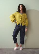 Woman wearing an acid yellow knit cardigan with bow tie front, and navy trousers