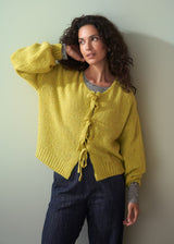 Woman wearing an acid yellow knit cardigan with bow tie front and navy trousers