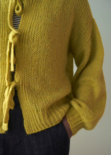 Close up of woman wearing acid yellow knit cardigan with bow tie front
