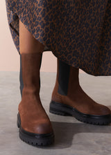 Brown knee-high boots worn with a leopard print skirt on a neutral background