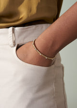 Gold bracelet on a wrist with a neutral background