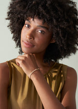 Woman wearing a gold sleeveless top against a neutral background