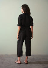 Woman wearing a black outfit standing against a plain background