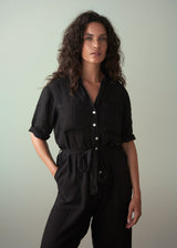 Woman wearing a black jumpsuit against a plain background