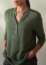 Person wearing a green long-sleeve shirt against a neutral background