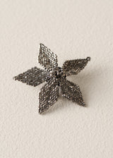 A small metallic flower-shaped accessory with five textured petals, shown on a plain light beige background.