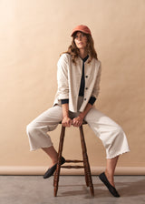 Woman wearing a cream jacket with black buttons against a beige background