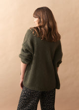 Woman wearing a green sweater against a beige background