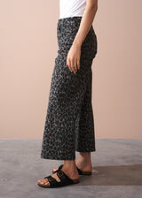 Person wearing khaki leopard print wide leg trousers on a plain background