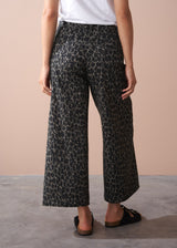 Person wearing khaki leopard print wide leg trousers on a neutral background