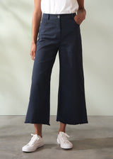 Person wearing navy wide leg trousers and white sneakers on a plain background