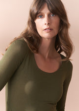 Woman wearing a green long-sleeve cashmere blend top against a beige background