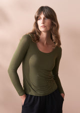 Woman wearing a green long-sleeve cashmere blend top against a beige background