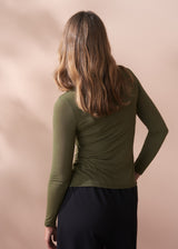 Person wearing a green long-sleeve cashmere blend top against a beige background