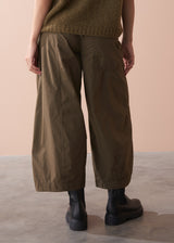 Woman wearing a green sleeveless top and wide-leg cargo trousers against a beige background