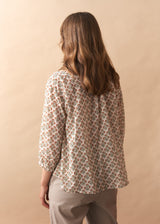 Person wearing a floral blouse against a beige background