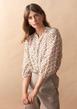 Close up of woman wearing a 3/4 sleeve patterned blouse with beige trousers