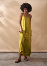 Woman wearing a scoop neck yellow satin maxi dress against a beige background