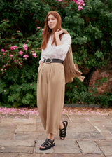 Woman wearing light beige cropped wide leg trousers, matching beige jacket and a white top.