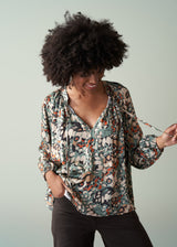 Woman wearing a floral blouse against a plain background