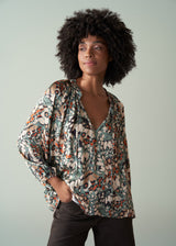 Woman wearing a patterned blouse against a plain background