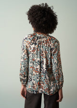 Person wearing a patterned blouse with a plain background