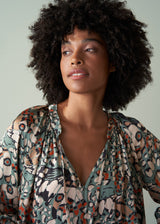 Woman wearing a patterned blouse against a plain background