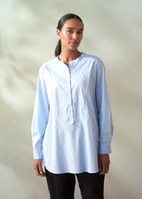 Woman wearing a light blue shirt against a plain background