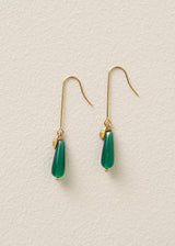 Green teardrop earrings with gold hooks on a light beige background