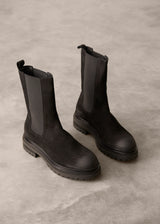 Pair of black Chelsea boots on a gray concrete surface