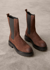 Pair of brown leather boots with black soles on a gray background