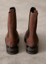 Brown leather boots with black soles on a beige background