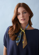 Woman wearing a patterned neck tie with blue jumper