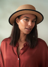 Woman wearing a straw hat with a black band against a plain background