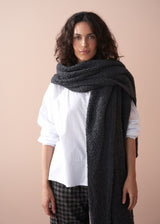 Woman wearing a large dark gray scarf against a beige background