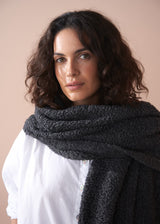 Woman wearing a dark gray scarf against a beige background
