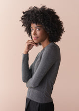 Woman wearing a silver metallic long sleeve top against a beige background