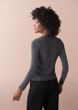 Woman wearing a silver metallic long sleeve top against a beige background