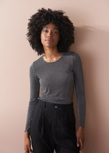 Woman wearing a silver metallic long sleeve top against a beige background