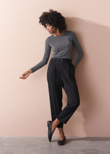 Woman wearing a silver metallic long sleeve top against a beige background