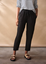 Women wearing a striped jumper with black tapered linen trousers